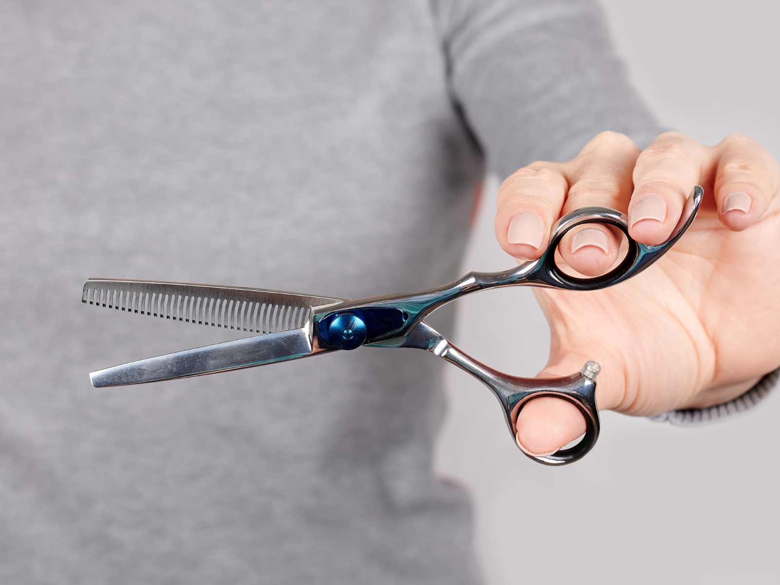 A salon hairstylist holding a pair of hair thinning scissors